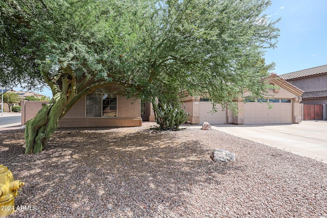 656 W Johnson Dr, Gilbert, AZ 85233 - view of property hidden behind natural elements featuring driveway, a garage, fence, and stucco siding