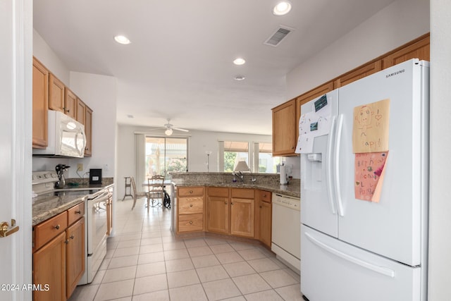 kitchen featuring dark stone countertops, white appliances, kitchen peninsula, light tile patterned floors, and ceiling fan