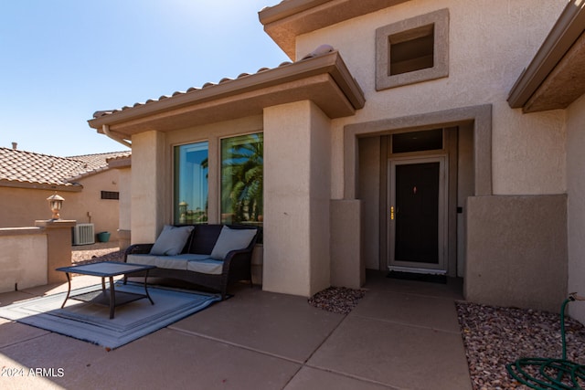 view of exterior entry featuring an outdoor hangout area, a patio area, and central air condition unit