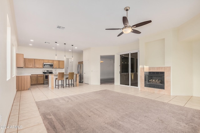 unfurnished living room featuring ceiling fan, light tile patterned flooring, and a fireplace