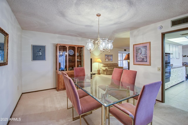 dining room featuring visible vents, baseboards, light colored carpet, an inviting chandelier, and a textured ceiling