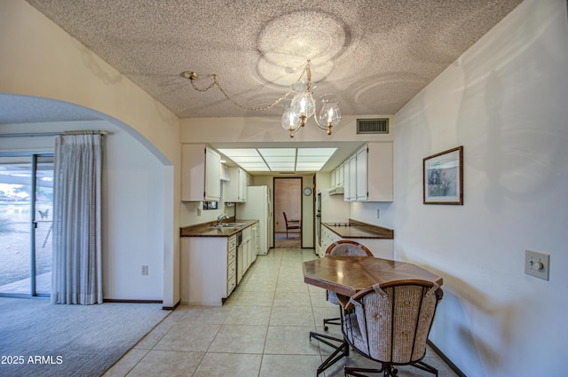 kitchen with visible vents, a notable chandelier, a sink, dark countertops, and arched walkways