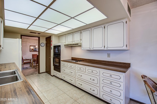 kitchen featuring visible vents, black appliances, under cabinet range hood, dark countertops, and light tile patterned flooring