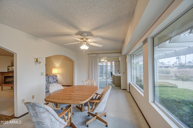 dining area with baseboards, arched walkways, ceiling fan, a textured ceiling, and light colored carpet