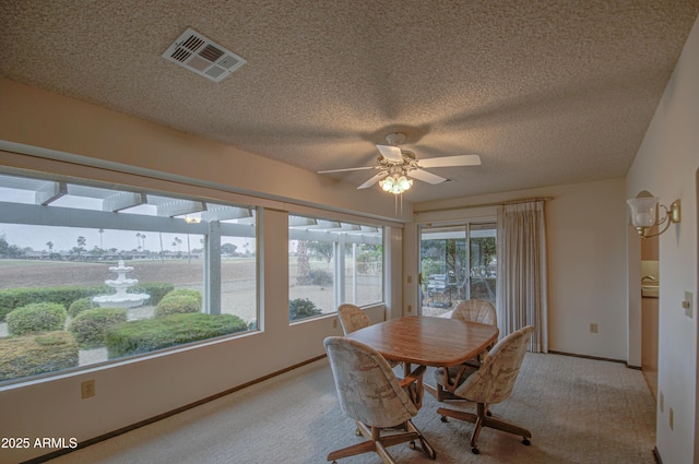 dining space featuring visible vents, light carpet, a textured ceiling, and a ceiling fan