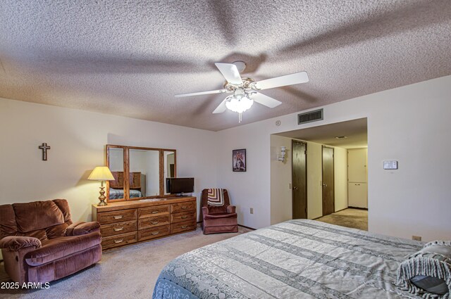 bedroom with ceiling fan, light colored carpet, visible vents, and a textured ceiling