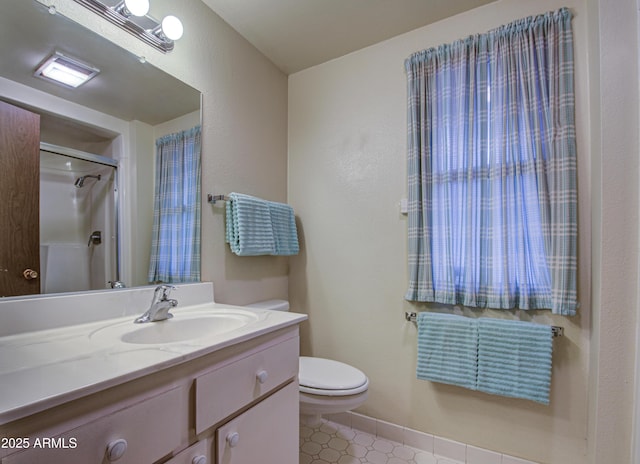 bathroom featuring a shower, toilet, vanity, and baseboards