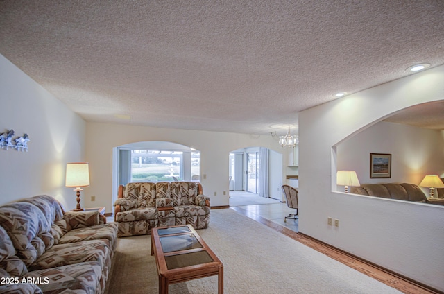 living room featuring a notable chandelier, recessed lighting, arched walkways, and a textured ceiling