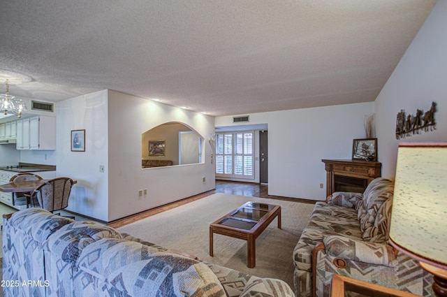 living area featuring baseboards, visible vents, and a textured ceiling