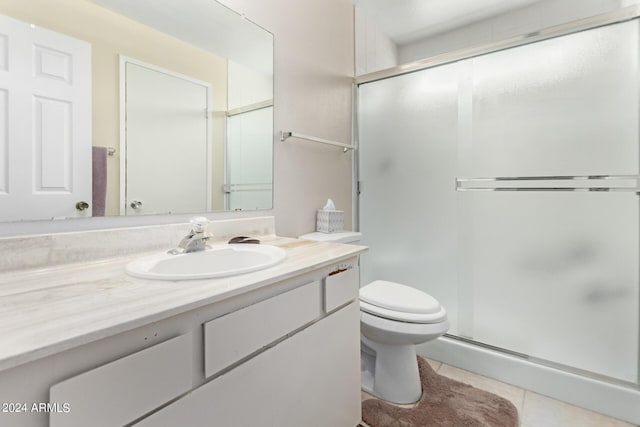 bathroom with tile patterned floors, a shower with door, toilet, and vanity