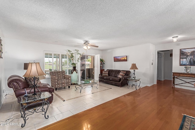 living room with ceiling fan, a textured ceiling, and light hardwood / wood-style flooring