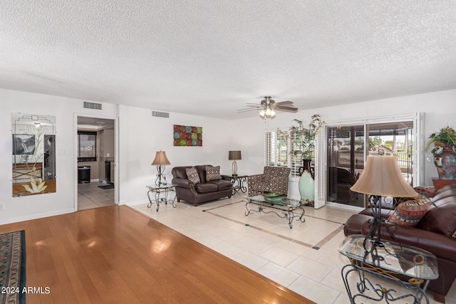 tiled living room with ceiling fan and a textured ceiling