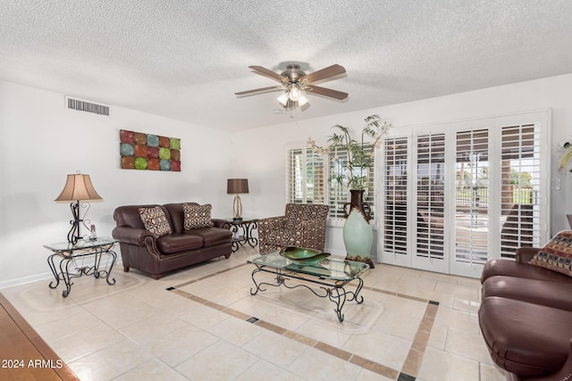 tiled living room with ceiling fan, plenty of natural light, and a textured ceiling