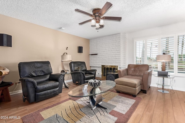 living room with ceiling fan, a textured ceiling, and light wood-type flooring