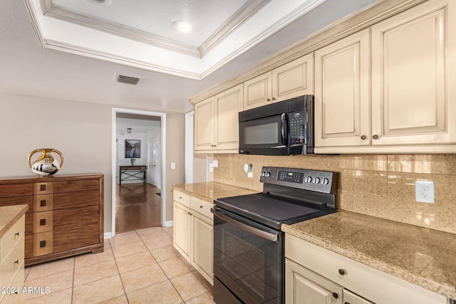 kitchen featuring light tile patterned floors, a raised ceiling, cream cabinets, and black appliances