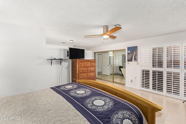 tiled bedroom with a textured ceiling, ceiling fan, and a closet