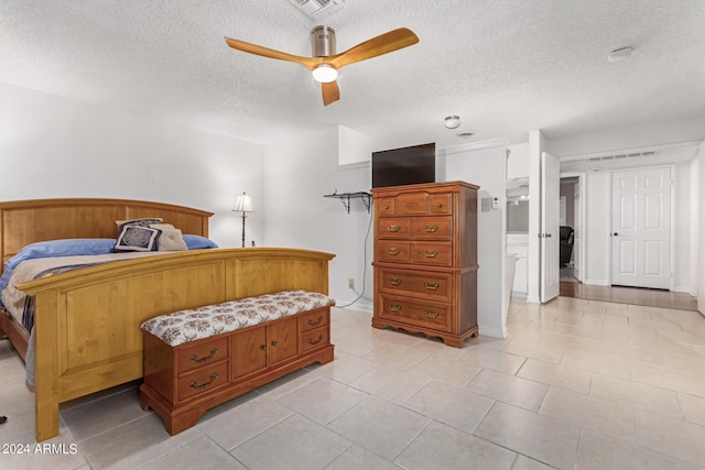 tiled bedroom featuring a textured ceiling, ceiling fan, and ensuite bathroom