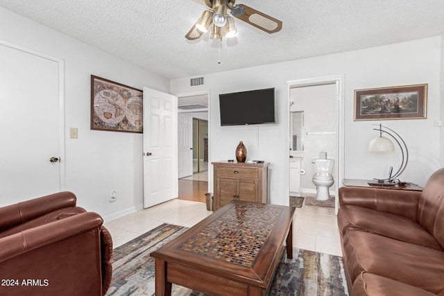 living room with ceiling fan, a textured ceiling, and light tile patterned flooring