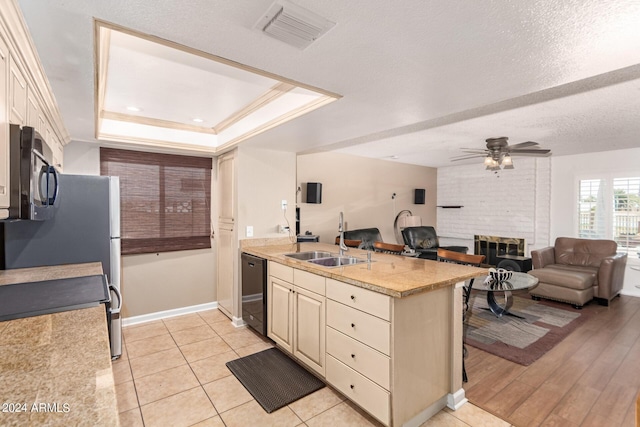 kitchen with ceiling fan, black appliances, sink, a tray ceiling, and light tile patterned floors