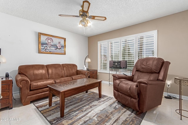 living room featuring ceiling fan, light tile patterned flooring, and a textured ceiling