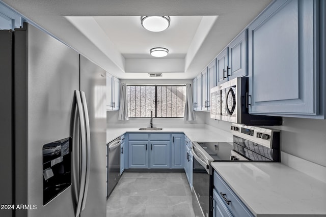 kitchen featuring blue cabinetry, sink, stainless steel appliances, and a tray ceiling