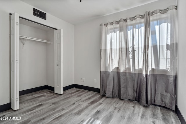 unfurnished bedroom with light hardwood / wood-style floors and a closet