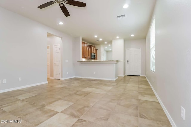 unfurnished living room featuring ceiling fan and light tile floors