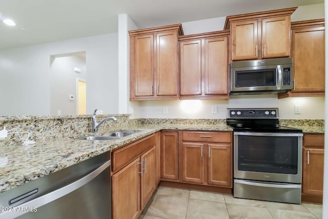 kitchen with light stone countertops, sink, light tile flooring, and appliances with stainless steel finishes