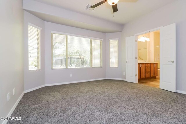 unfurnished bedroom featuring light colored carpet, ensuite bathroom, and ceiling fan