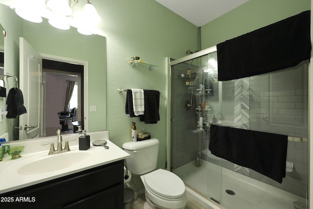 bathroom with toilet, vanity, and a shower with door