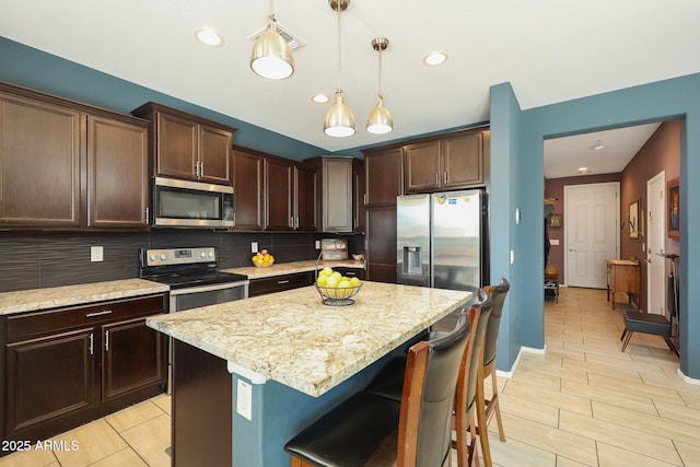 kitchen featuring hanging light fixtures, stainless steel appliances, a kitchen island, and tasteful backsplash