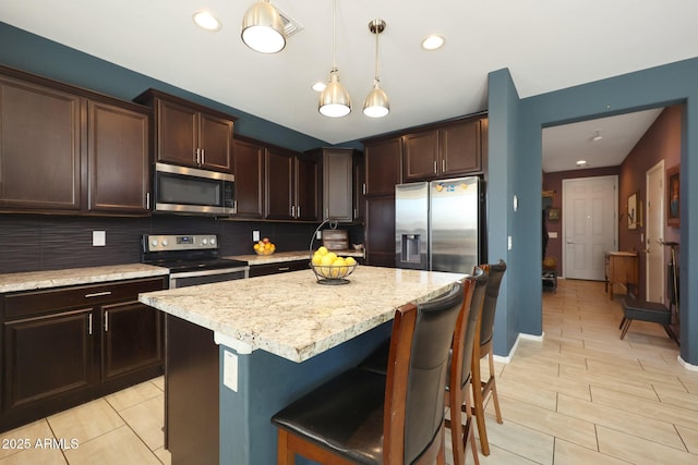 kitchen with tasteful backsplash, a kitchen island, dark brown cabinetry, hanging light fixtures, and appliances with stainless steel finishes