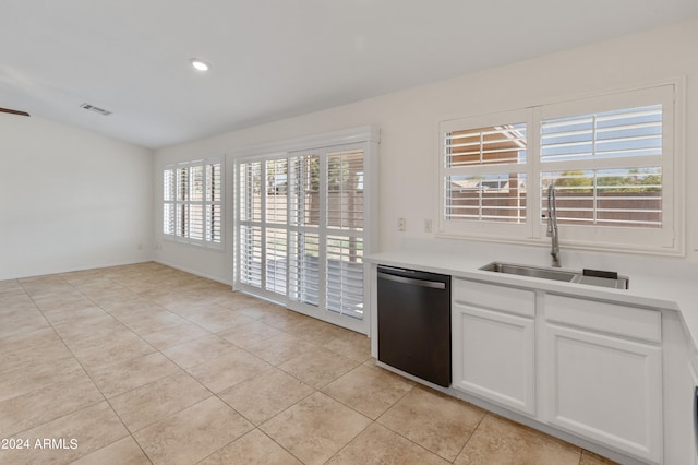 kitchen with stainless steel dishwasher, sink, light tile patterned floors, and white cabinets