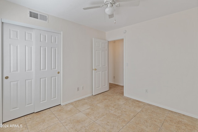 unfurnished bedroom with light tile patterned flooring, ceiling fan, and a closet