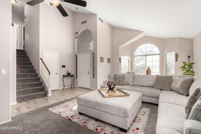 living area featuring high vaulted ceiling, stairway, wood finished floors, and visible vents