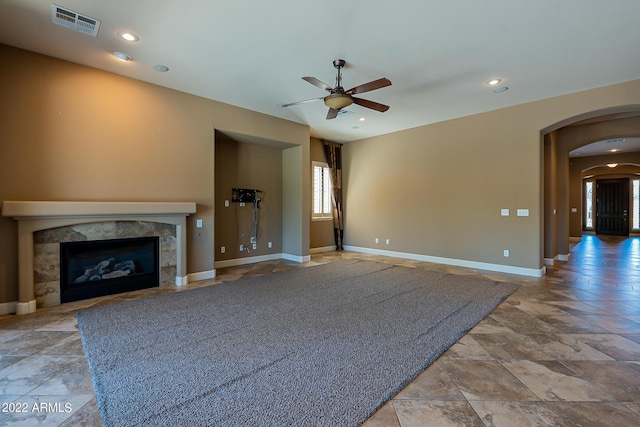 4120 E Woodside Way, Gilbert, AZ 85297 - unfurnished living room featuring arched walkways, ceiling fan, a high end fireplace, stone finish flooring, and recessed lighting