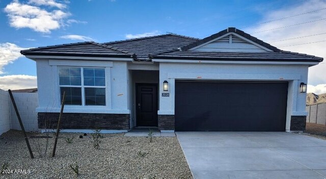 ranch-style house featuring a garage, a tile roof, stucco siding, and concrete driveway