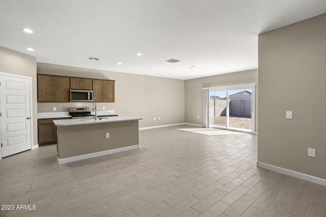 1471 S 239th Dr, Buckeye, AZ 85326 - kitchen with appliances with stainless steel finishes, light wood-style flooring, an island with sink, light countertops, and open floor plan