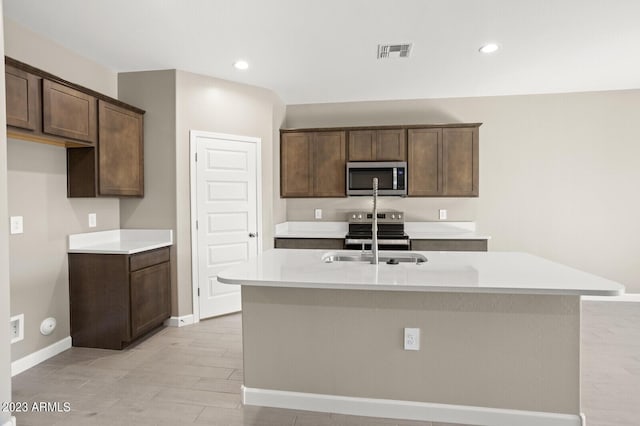1471 S 239th Dr, Buckeye, AZ 85326 - kitchen with stainless steel appliances, a kitchen island with sink, dark brown cabinets, light countertops, and recessed lighting