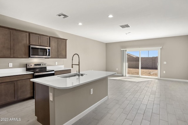 1471 S 239th Dr, Buckeye, AZ 85326 - kitchen featuring stainless steel appliances, a sink, baseboards, light wood-type flooring, and a kitchen island with sink