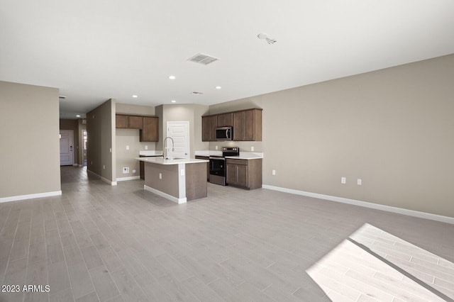1471 S 239th Dr, Buckeye, AZ 85326 - kitchen with stainless steel appliances, open floor plan, baseboards, a sink, and an island with sink