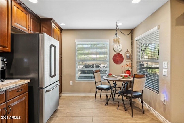 kitchen featuring a healthy amount of sunlight, pendant lighting, light hardwood / wood-style flooring, and high end fridge