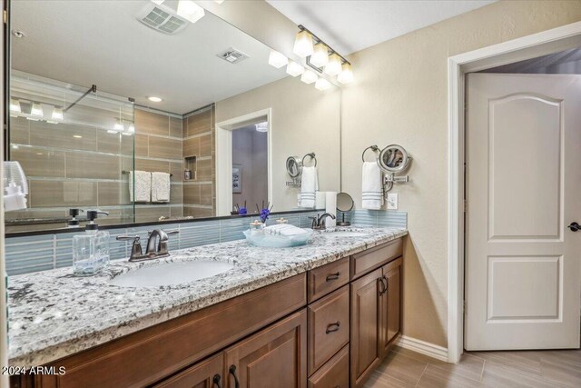 bathroom with decorative backsplash, walk in shower, and vanity