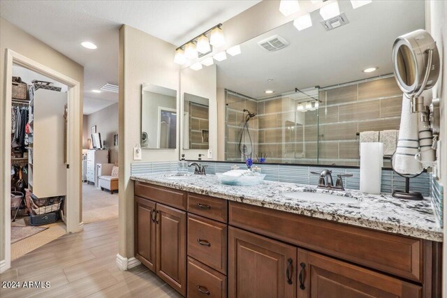 bathroom with a tile shower, wood-type flooring, and vanity