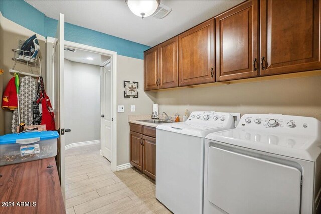 washroom with cabinets, light wood-type flooring, sink, and washer and dryer