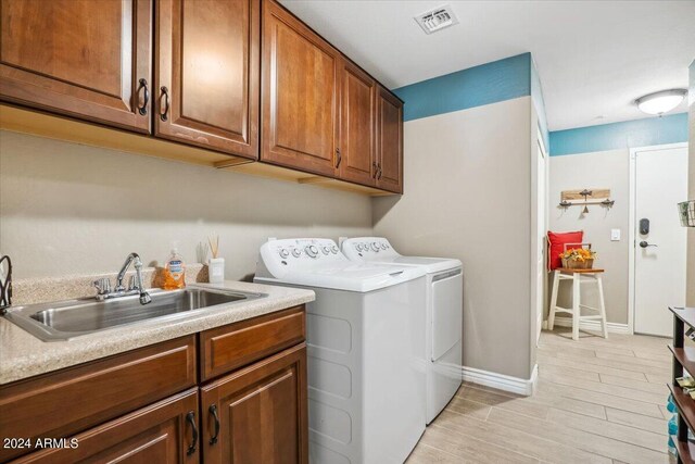 washroom featuring cabinets, light hardwood / wood-style floors, washer and dryer, and sink