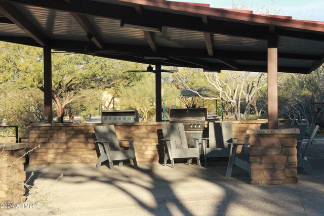 view of patio / terrace featuring ceiling fan, a bar, and an outdoor kitchen