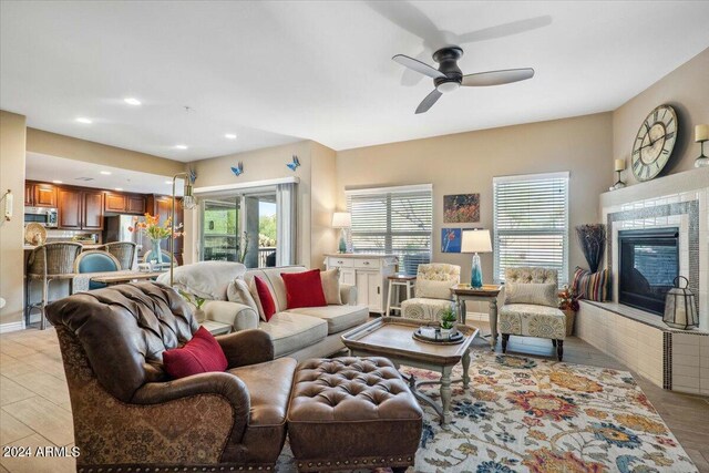 living room with a tile fireplace, light hardwood / wood-style floors, and ceiling fan