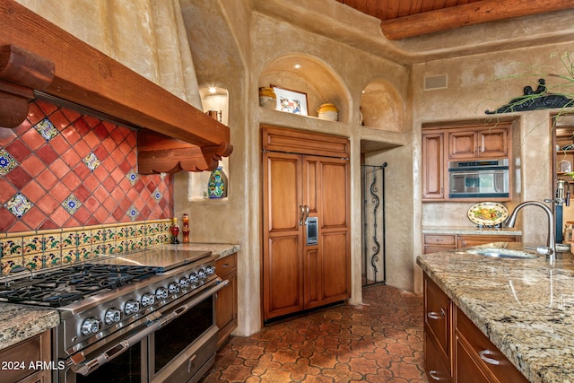 kitchen with sink, beam ceiling, stainless steel appliances, light stone counters, and tasteful backsplash