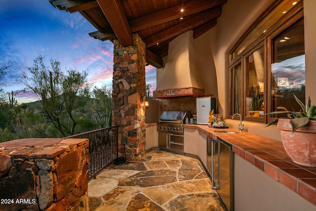 patio terrace at dusk with a grill, area for grilling, and sink